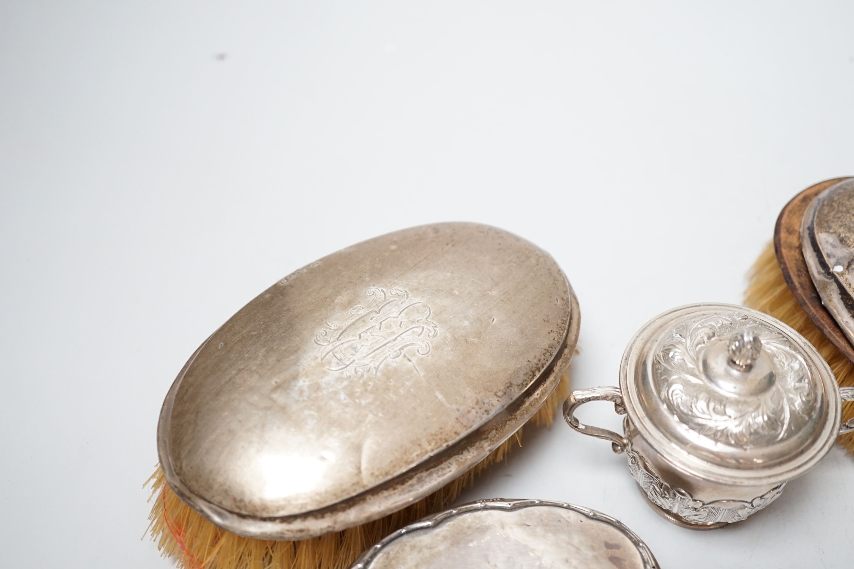 A small George V silver twin handled cup and cover, London, 1929 and three silver mounted brushes.